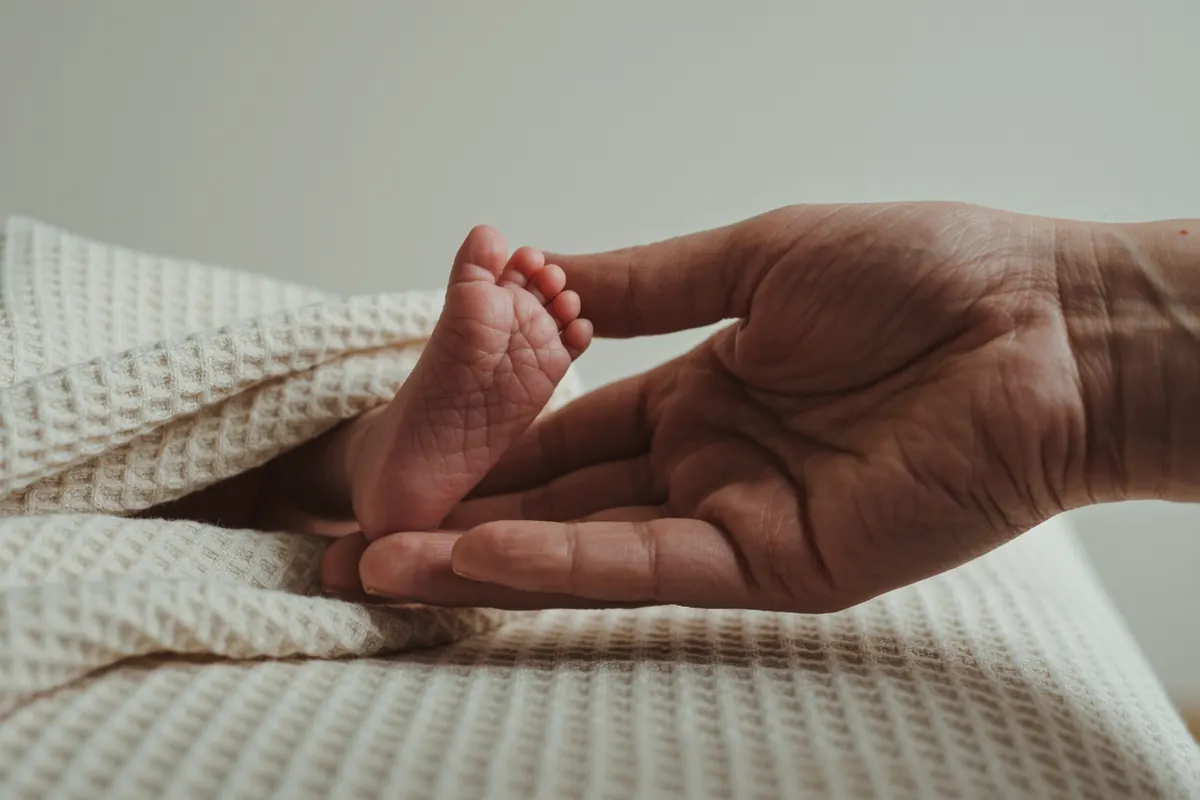 Pied de bébé tenu entre les doigts d'un adulte lors d'un toucher réflexe très doux